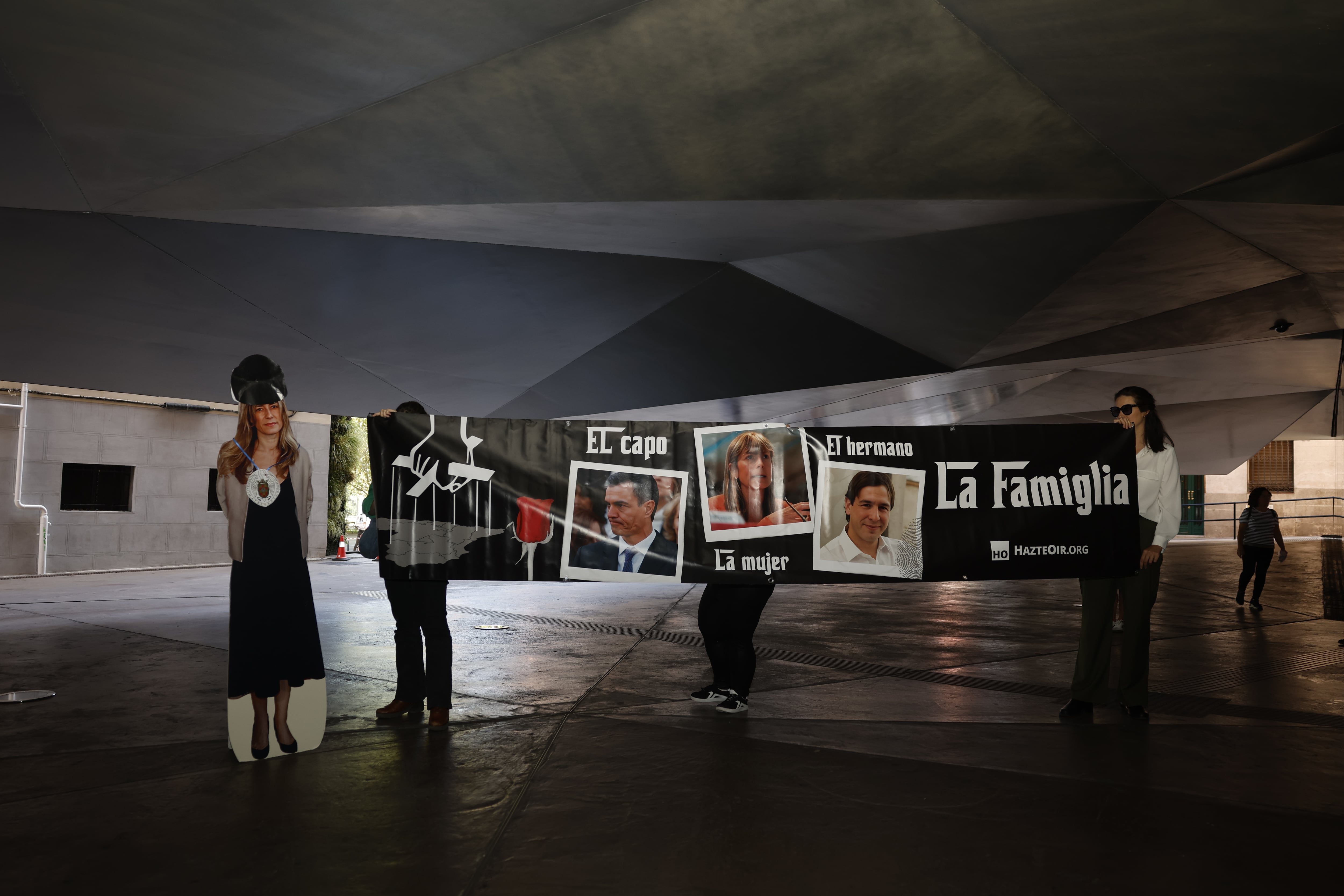 Tres personas sujetan una pancarta este martes en el CaixaForum de Madrid. 