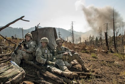 Soldados americanos hacen guardia detrás de un tocón de árbol mientras esperan que un helicóptero se evacue cuerpo del sargento Larry Rougle, muerto en una emboscada el valle de Korengal en Afganistán en octubre de 2007.