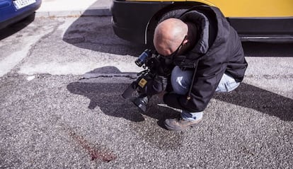 Un reportero de televisi&oacute;n toma im&aacute;genes de los restos de sangre del expolic&iacute;a apu&ntilde;alado por la espalda en Torremolinos. 