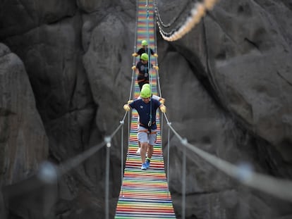 Varias personas cruzan un puente colgante de las Lomas del Mirador, en San Juan de Lurigancho (Perú).