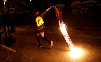 Un manifestante con una bandera en llamas despu&eacute;s de la elecci&oacute;n de Trump, en California.