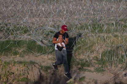 Un migrante carga a su bebé tras de cruzar el río Bravo en la frontera entre Estados Unidos y México, en abril de 2024.