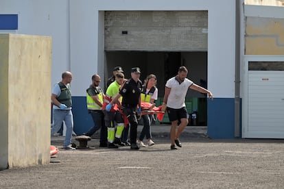 Agentes de Policía Nacional llevan en una camilla a uno de los migrantes que viajaba en el cayuco que ha volcado.