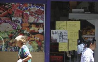 Dos personas caminan frente a un supermercado con avisos de promocin ayer, en el centro de Buenos Aires (Argentina).