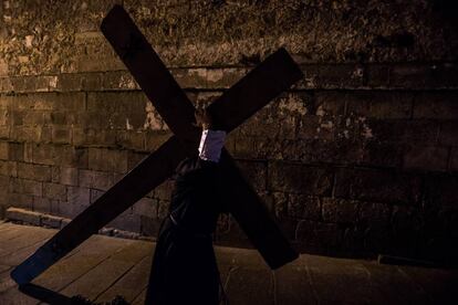 Un nazareno carga con la cruz en la procesión del Jesús Flagelado de Jueves Santo en Santiago de Compostela.