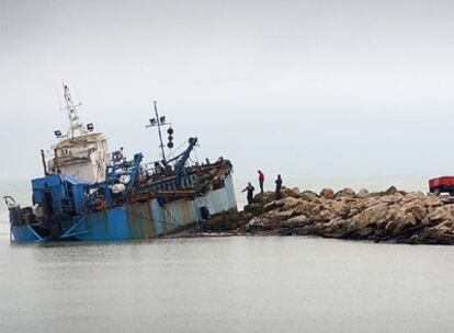 Varios técnicos observan ayer la draga encallada en la escollera del puerto de Cullera.