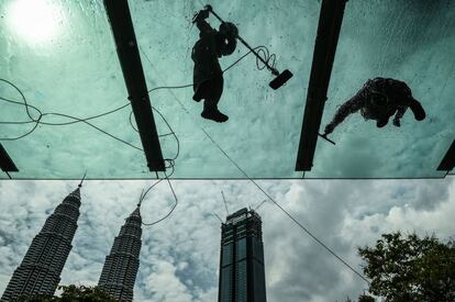 Dos trabajadores limpian un edificio próximo a las torres Petronas en Kuala Lumpur (Malasia),