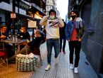 People wearing protective masks walk past bar customers after bars reopened in Spain's Basque Country, amid the coronavirus disease (COVID-19) outbreak, in Bilbao, Spain, February 19, 2021. REUTERS/Vincent West