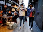 People wearing protective masks walk past bar customers after bars reopened in Spain's Basque Country, amid the coronavirus disease (COVID-19) outbreak, in Bilbao, Spain, February 19, 2021. REUTERS/Vincent West