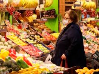 Una mujer compra en un puesto de frutas y verduras.