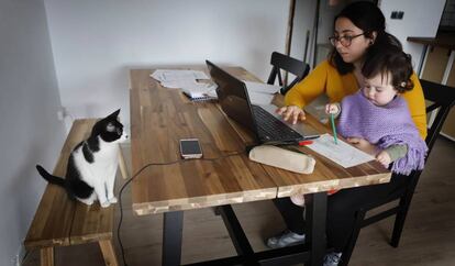 Una dona fa teletreball a casa mentre s'ocupa de la seva filla, a Terrassa.