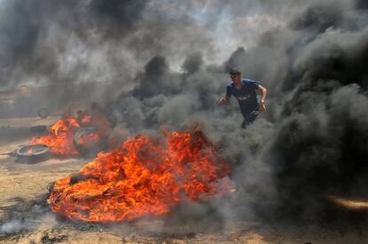 Um palestino enfrenta a fumaça gerada pela queima de pneus durante o protesto na fronteira entre Gaza e Israel.