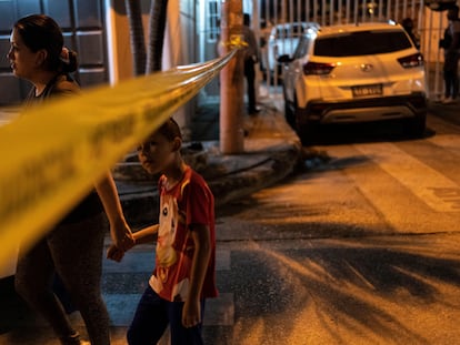 Una mujer y un niño atraviesan un cordón policial en Guayaquil.