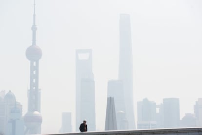 Un obrero en un puente frente al distrito financiero de Pudong, en Shangai (China).