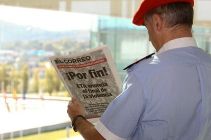 Un ertzaina lee un periódico tras el anuncio del cese definitivo de ETA.