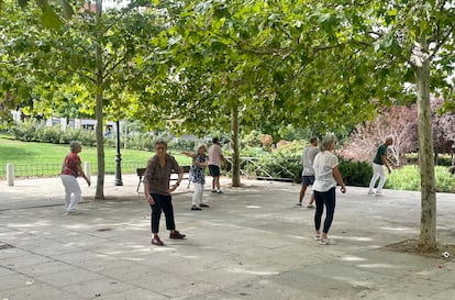 Varios hombres y mujeres participan en un clase guiada de taichí en el Parque de la Cornisa, Madrid. 