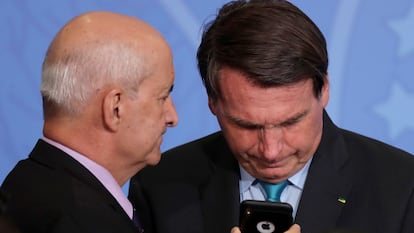 Bolsonaro olha telefone segurado pelo ministro da Secretaria-Geral da Presidência, Luiz Eduardo Ramos, em setembro de 2020.