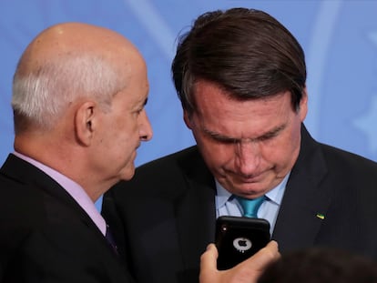 Bolsonaro olha telefone segurado pelo ministro da Secretaria-Geral da Presidência, Luiz Eduardo Ramos, em setembro de 2020.