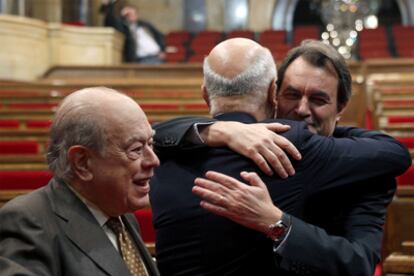 El nuevo presidente catalán, Artur Mas, se abraza a su compañero Duran Lleida en presencia del ex presidente Jordi Pujol, ayer.