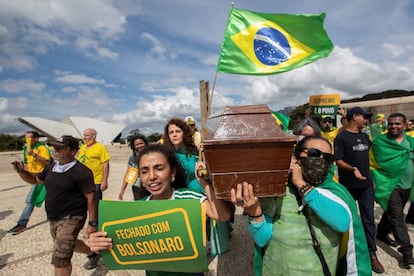 Sem partido e praticamente sem base parlamentar, Bolsonaro se apoia a uma parcela da população capaz de arriscar a própria saúde em meio à pandemia do novo coronavírus, contrariando orientações de manter o isolamento social, para mostrar seu apoio ao Governo. Na imagem: manifestantes carregam caixão em ato em prol do presidente, em Brasília.