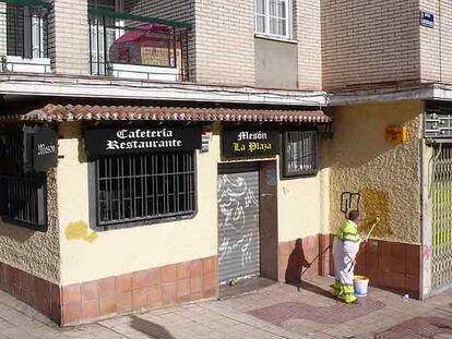 Un empleado municipal tapa las pintadas de la fachada del mesón La Plaza tras el homicidio.