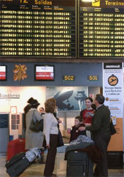 Un grupo de pasajeros observa en las pantallas los retrasos en los vuelos este mediodía en Barajas.