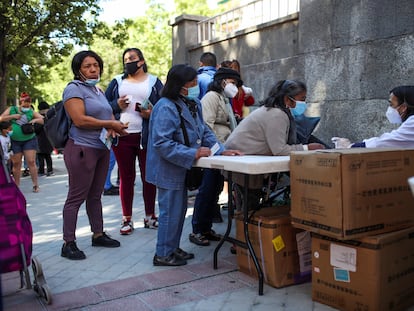 Decenas de personas acuden al reparto de alimentos que la Fundación Madrina realiza en la plaza San Amaro, en Madrid.