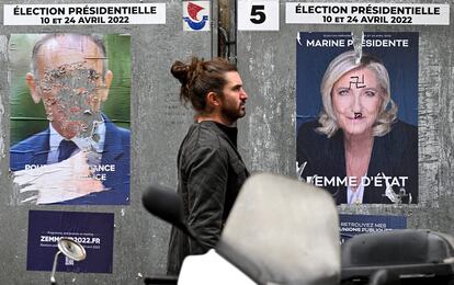 Un ciudadano pasa entre dos carteles vandalizados de Zemmour y Le Pen, el 30 de marzo en París.