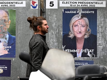 Un ciudadano pasa entre dos carteles vandalizados de Zemmour y Le Pen, el 30 de marzo en París.