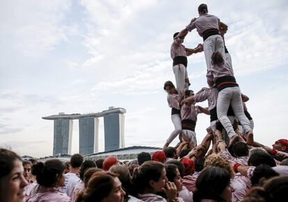 Castellers trepan durante la formación de un castell en el distrito financiero de Singapur.