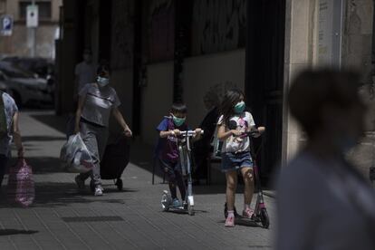 El uso será obligatorio para “las personas de seis años en adelante”, con lo que afectará a unos 45 millones de personas. En la imagen, dos niños pasean con sus patinetes por una calle de Barcelona.