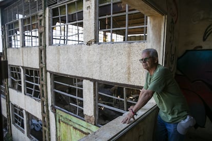 El exminero José García López asomado a una de las ventanas del lavadero donde trabajó desde los 18 años. La instalación está completamente abandonada, con los cristales rotos, llena de pintadas y con la techumbre, de uralita, a medio caer