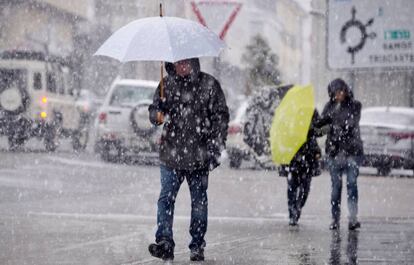 Varias personas caminan bajo una intensa nevada, ayer lunes en la localidad lucense de Piedrafita do Cebreiro.