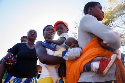 Votantes llevan a los niños en brazos mientras hacen cola en la mesa de votación donde el presidente de Zimbabue depositará su voto en la escuela primaria de Sherwood, en Kwekwe. 