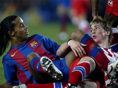 Ronaldinho y Fernando Torres, hechos un lío sobre el césped tras un encontronazo.