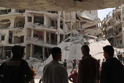 Miembros de la Defensa Civil Siria buscan entre los escombros de un edificio afectado por una explosión, en Yisr al-Shugur (Siria). 