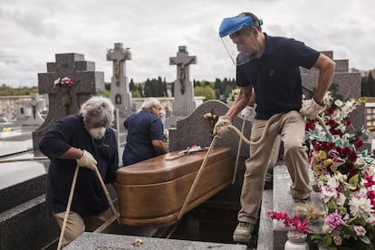 Enterradores bajan el ataúd de Manuela Revuelta, fallecida como consecuencia del coronavirus a la edad de 94 años en una residencia de ancianos. Cementerio de la Almudena, Madrid, 7 de abril de 2020. / ALEJANDRO MARTÍNEZ VÉLEZ