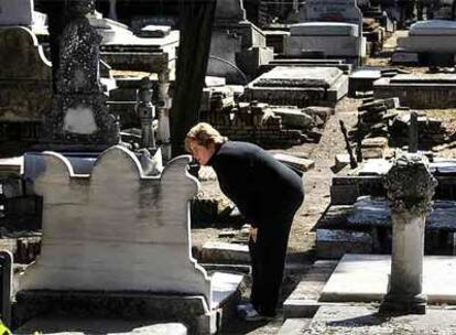 Una mujer observa una tumba en un cementerio civil.