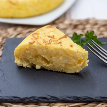 Portion of Spanish omelette, homemade, on a black plate.  In Jaen, Andalucia, Spain