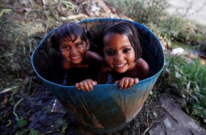 Unas niñas se bañan dentro de un barril en Nueva Delhi, India.