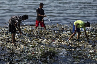 Niños buscan entre la basura en el agua en Indonesia.
