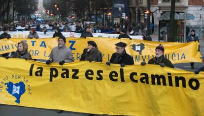 Un grupo de personas porta las diversas pancartas que Gesto por la Paz ha empleado a lo largo de su historia.