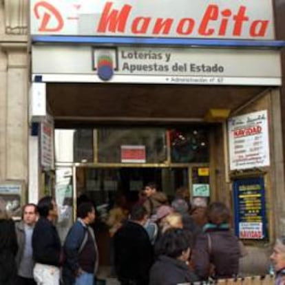 Numerosas personas aguardan hoy en una cola para comprar unos décimos de lotería de Navidad en la conocida administración 'Doña Manolita' de la Gran Vía madrileña.