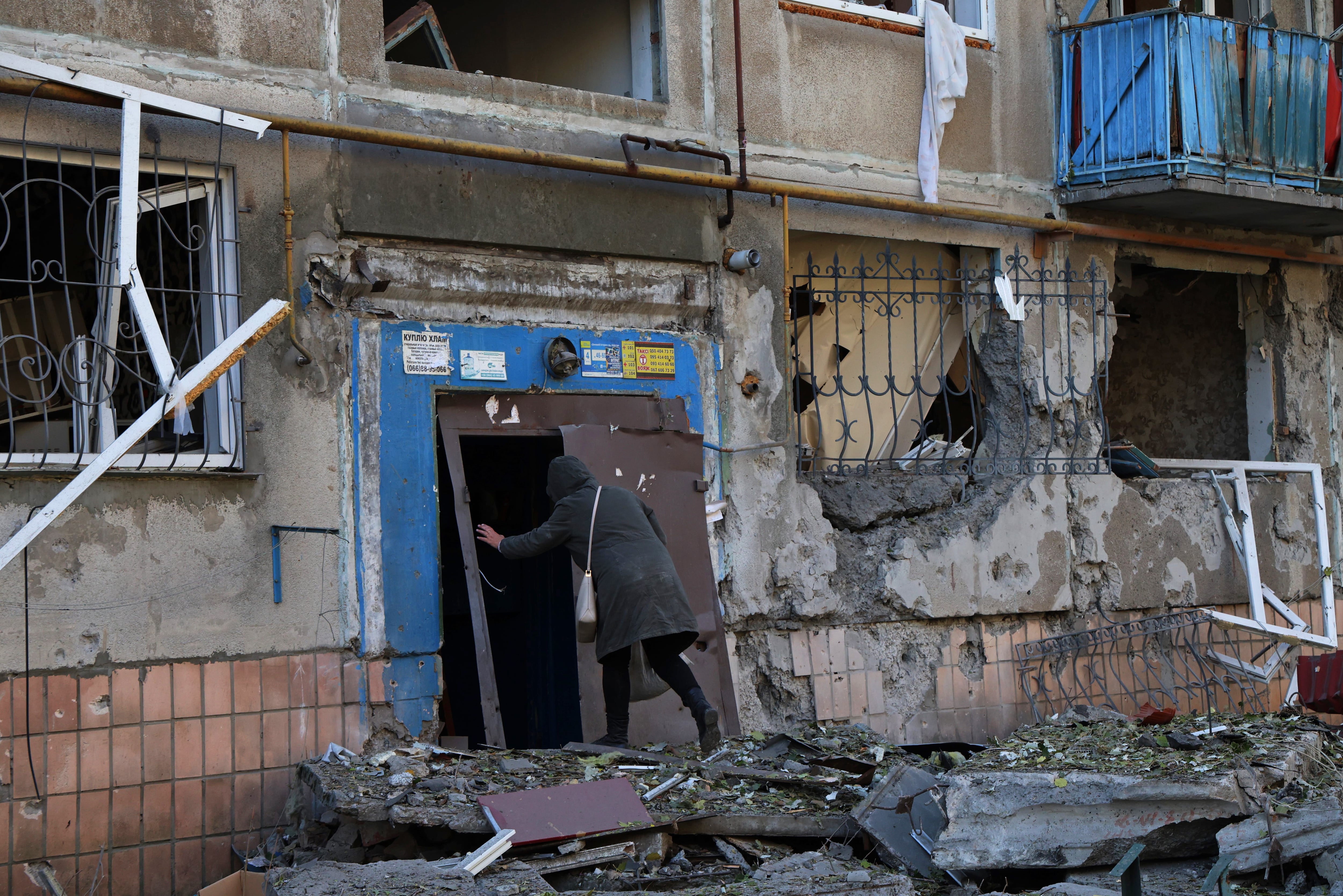 Una mujer regresa al edificio bombardeado donde habita tras recoger algo de comida en Kostiantinivka.
