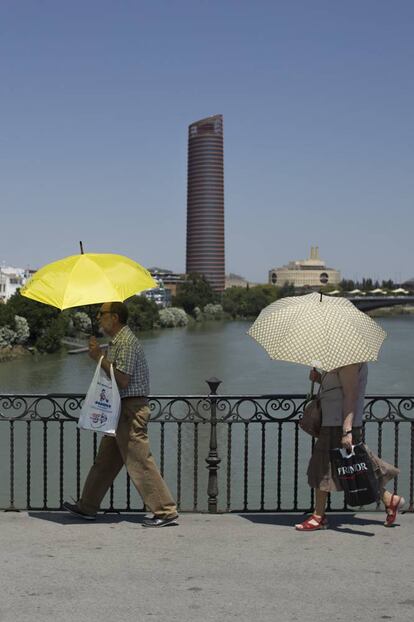 Un hombre y una mujer se protegen del sol con un paraguas en Sevilla.