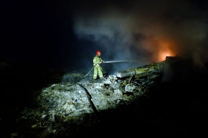 Los bomberos trabajan enfriando los restos del avi&oacute;n ya de noche.