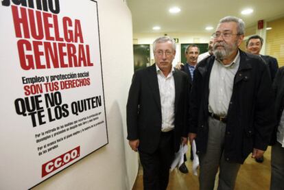 Toxo y Méndez pasan frente a un cartel que convoca a la huelga general.