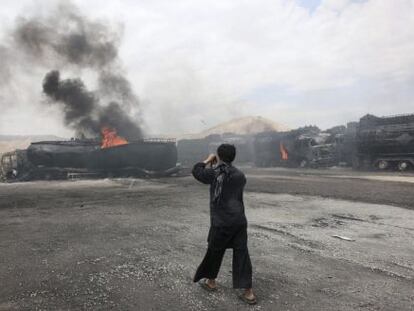 Un hombre fotografía los camiones atacados por los talibán.