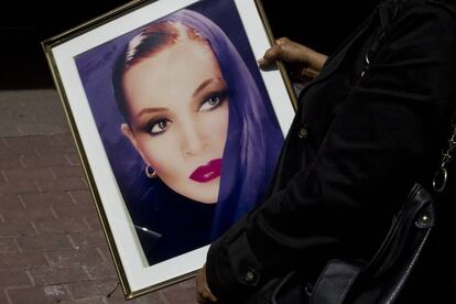 Una mujer sostiene el retrato de Sara Montiel que presidió su coche fúnebre.