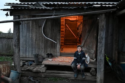 Izhmukhametov, de 9 años, se sienta frente a la casa de su familia a pasar la tarde, solo ya que no tiene con quien jugar.